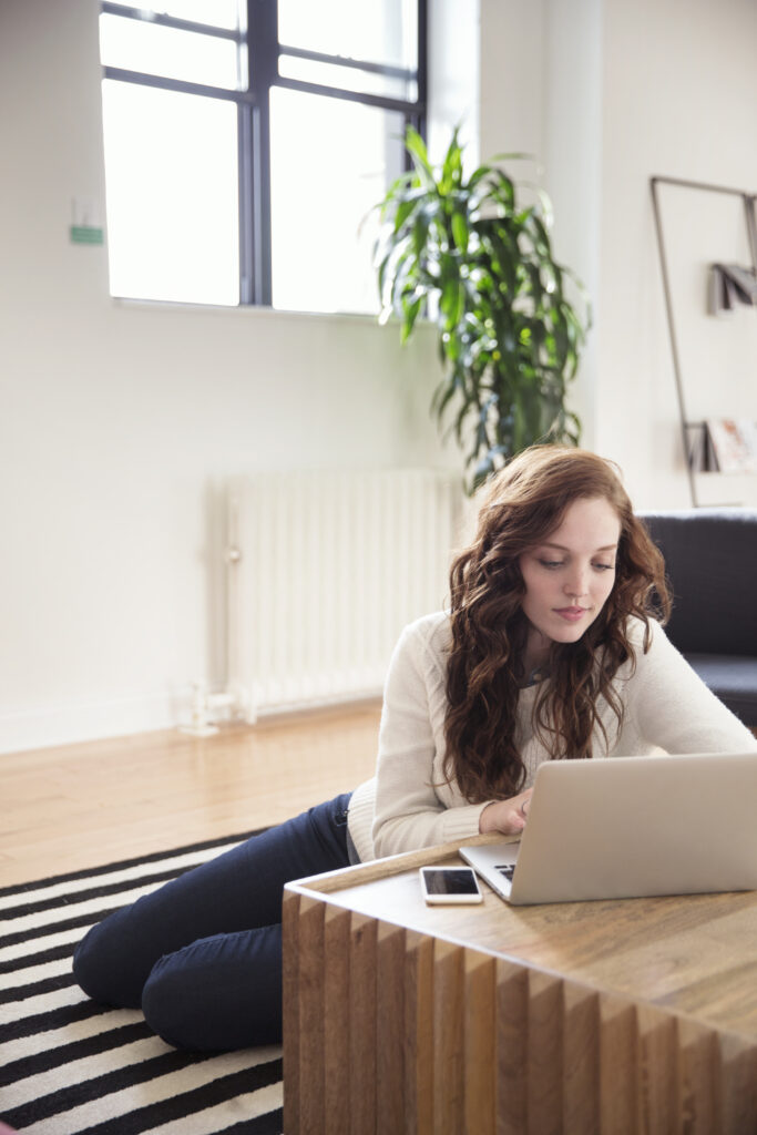 Businesswoman Using Laptop While Sitting On Carpet In Office