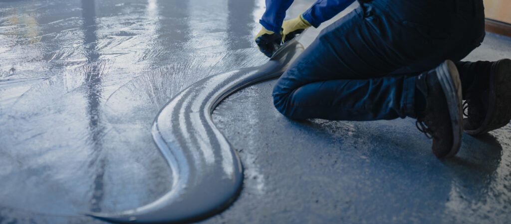 The worker applies gray epoxy resin to the new floor